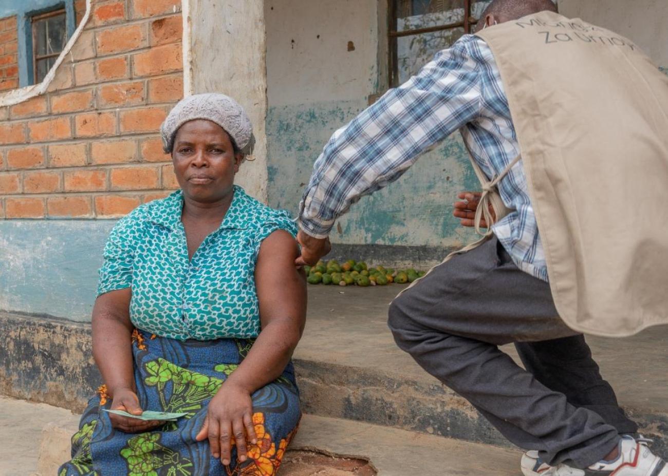 Egrita gets her COVID-19 vaccine, right at home in Kasungui, central Malawi, thanks to a UNICEF supported COVID-19 expression vaccination campaign