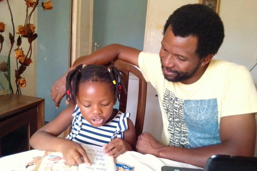 Mazunzo listens as his five-year-old daughter Mathando reads
