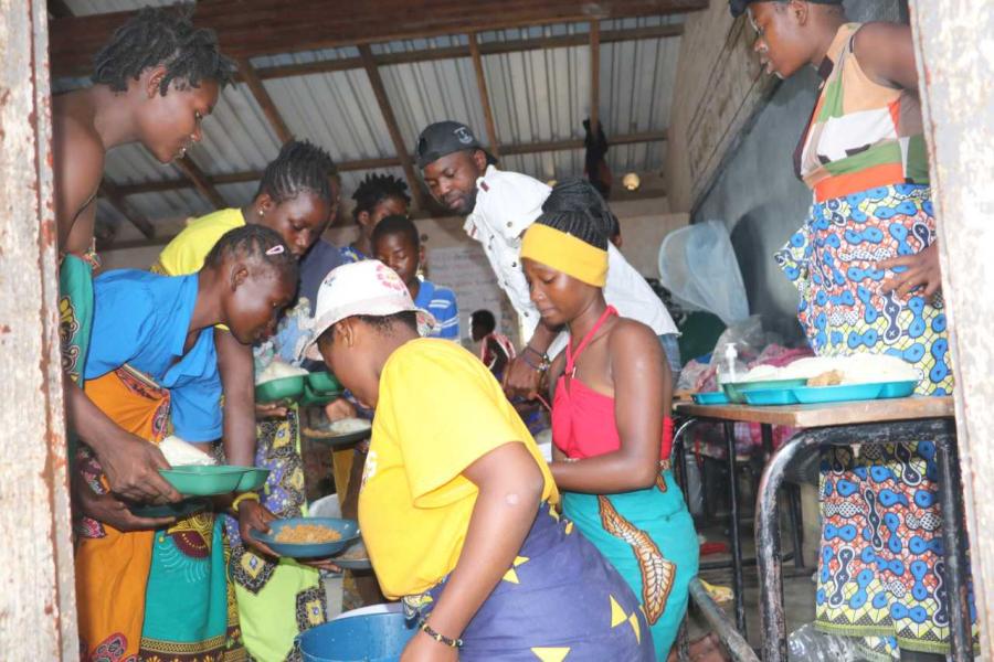 Volunteers help serve food at the Manja displacement site