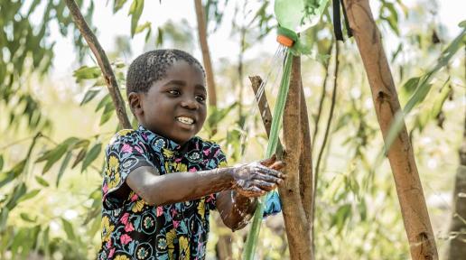 Olive's son, five-year-old Phineas Mpomba washing his hand by the tippy-tap constructed by chikondi caregroup members under Afikepo. This initiative ensures access to clean water for proper hygiene after toilet use.